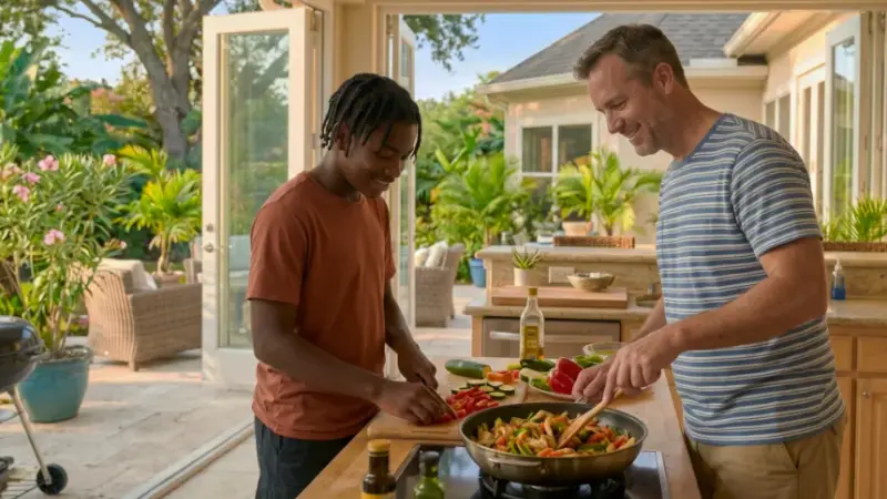 A teenage young man and his foster father cooking a stir-fry together at a sunlit kitchen island